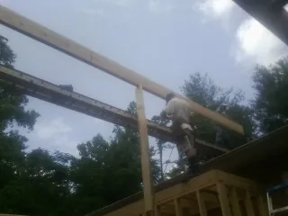 Carpenter setting a ridge beam over a new addition frame — Ice Dam Removal by Roofing Brothers in Purdys