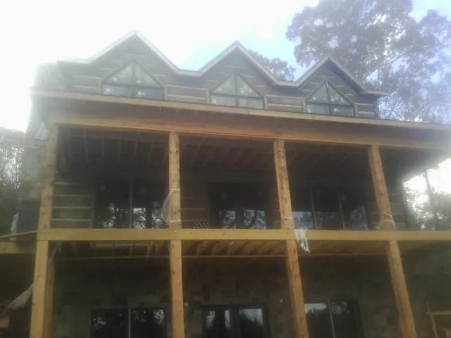 Dormers and porch framing on a large log home under construction — Roof Coating work by our crew in Purdys