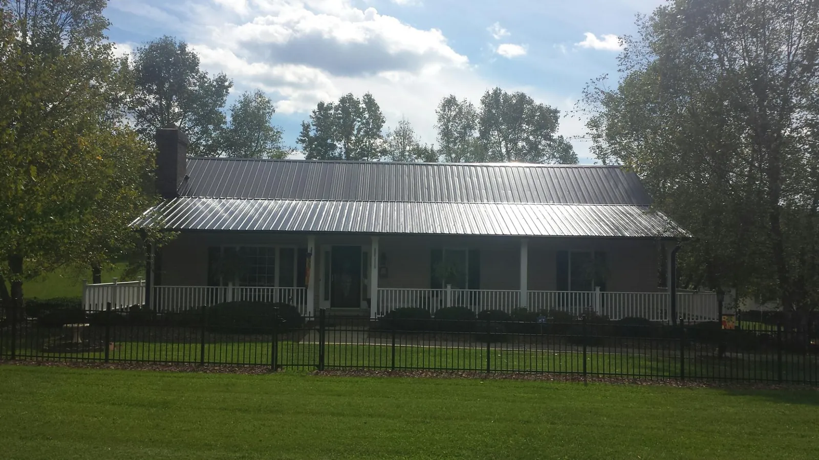 Gray metal roof on a brick ranch with a full width front porch — Gutter Guard Installation work by our crew in Purdys