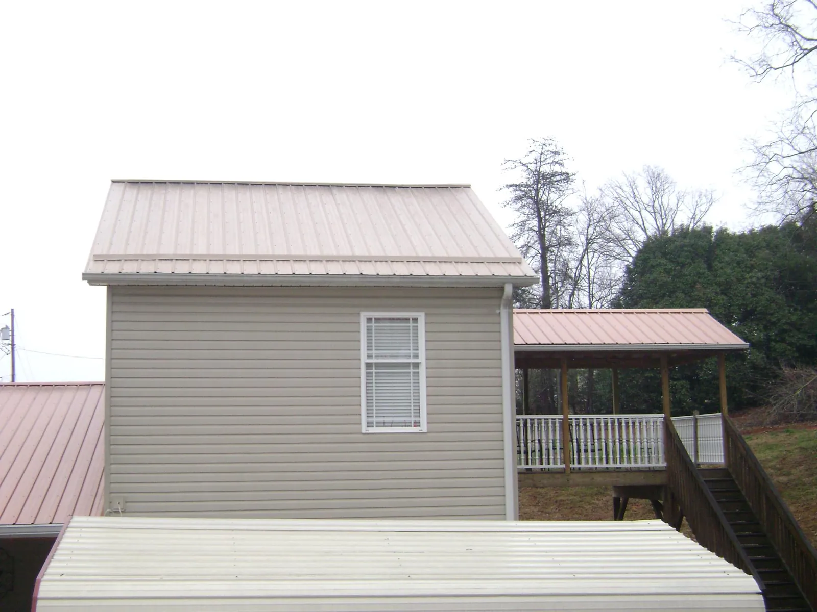 Tan metal roofs on a two story addition and attached porch, from a Roof Replacement job in Purdys