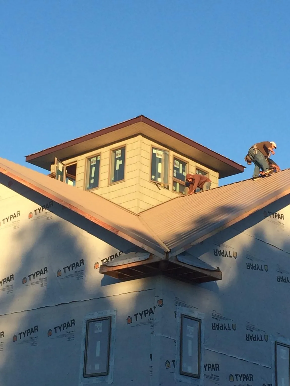 Roofers working around a rooftop cupola on a new metal roof at sunset — Roof Waterproofing in Purdys by Roofing Brothers